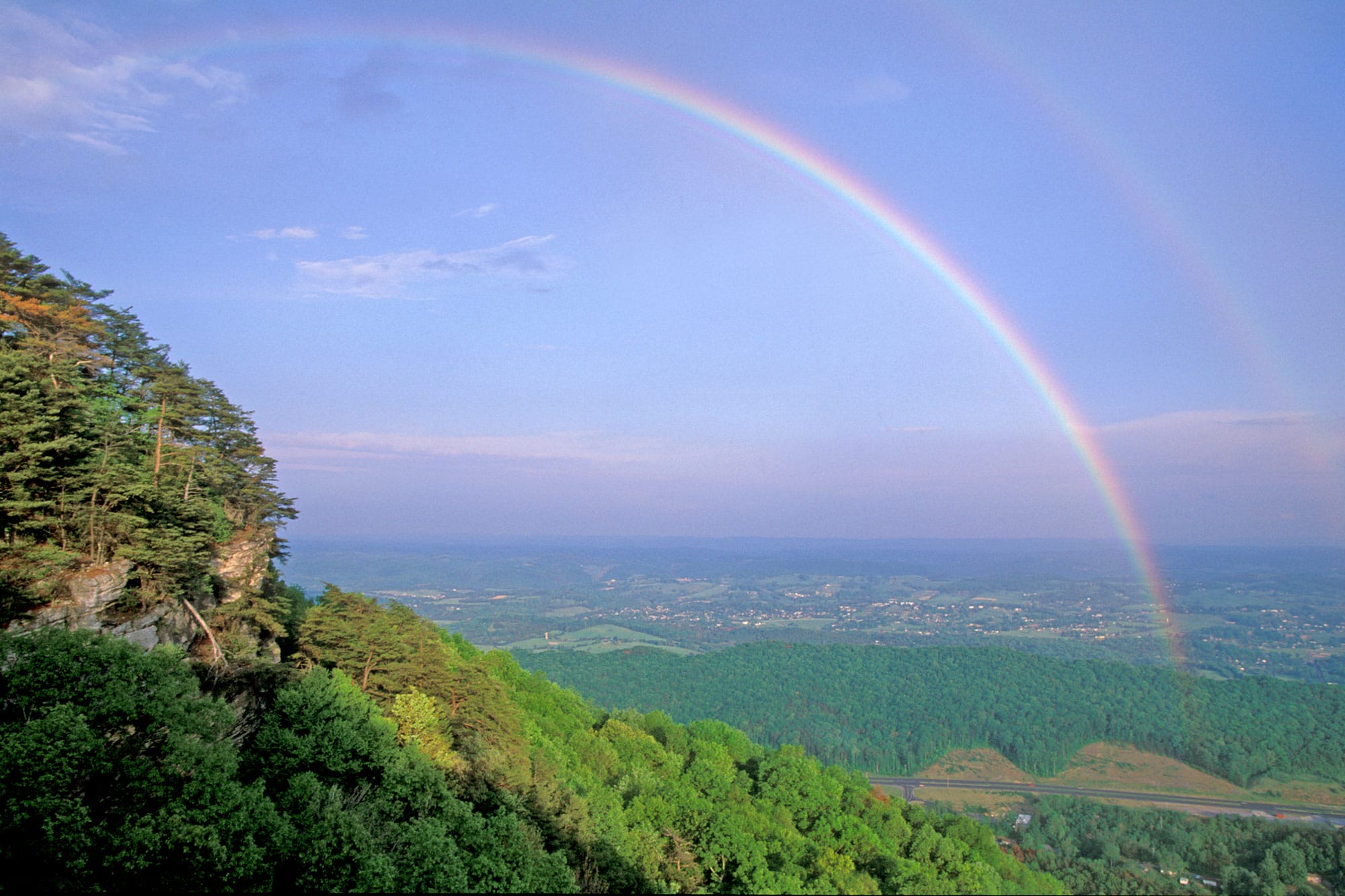 A rainbow is seen over a valley.