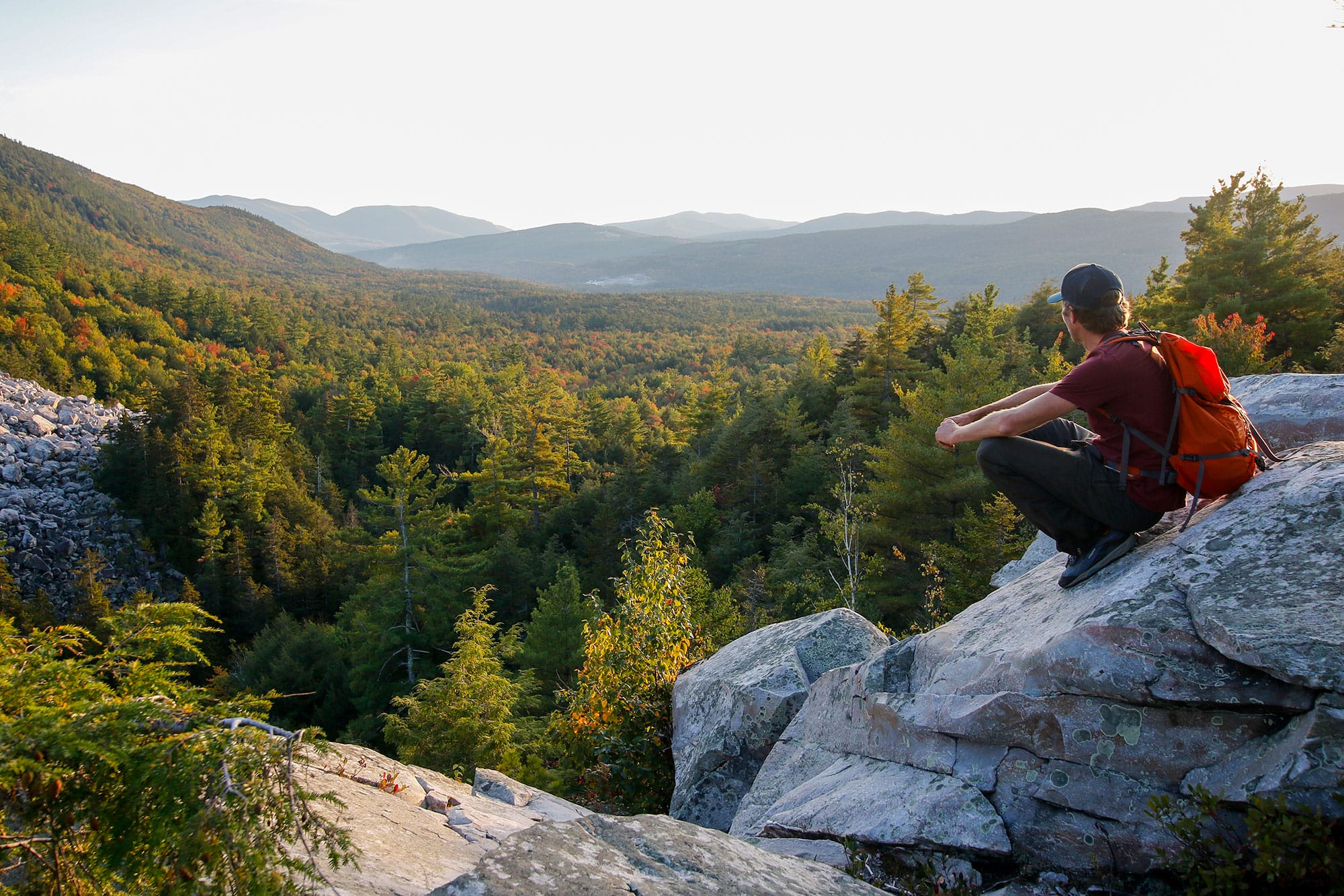 A man sitting on a rock overlooking a valley.