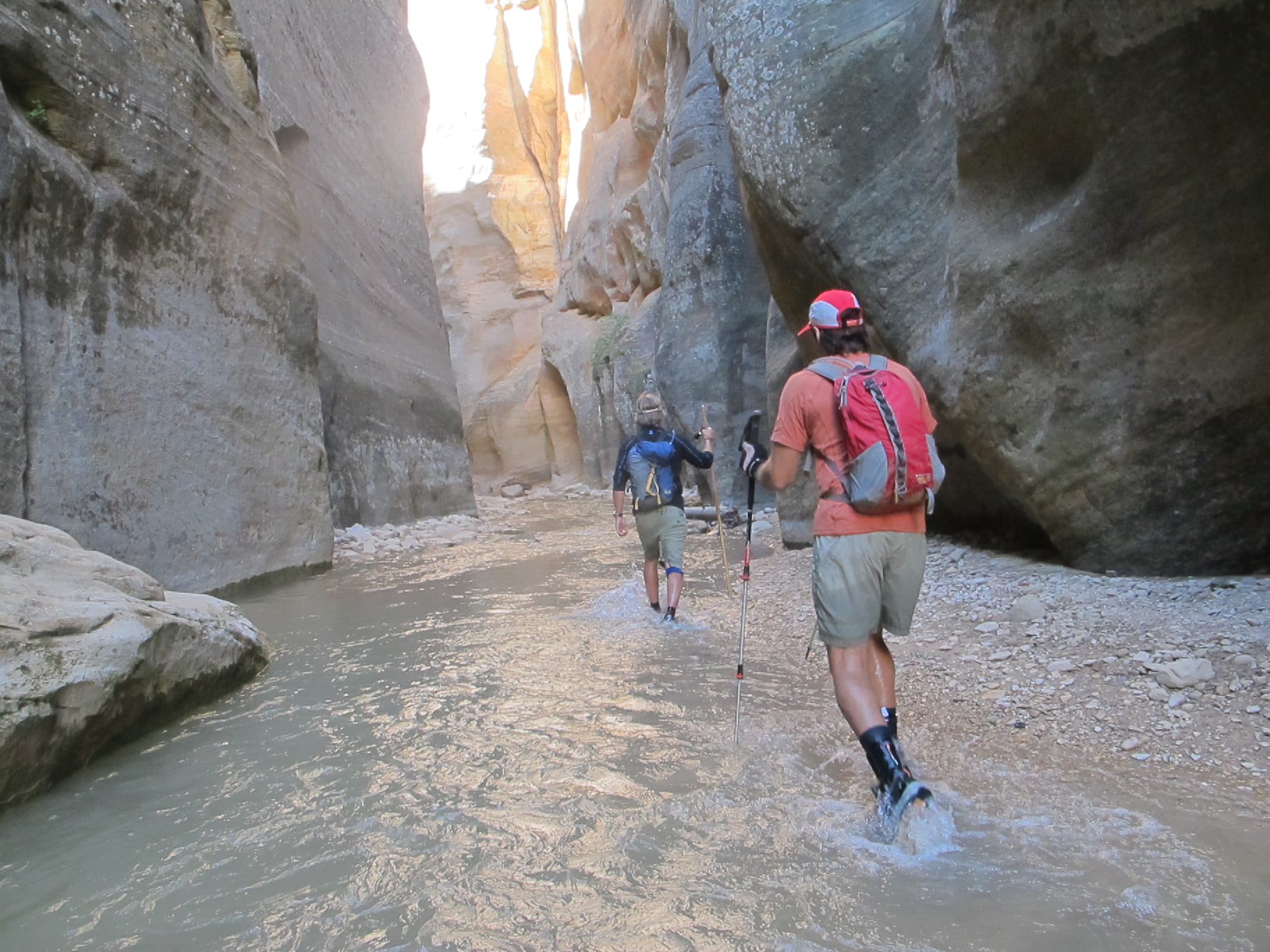 Two people hiking through a narrow canyon.