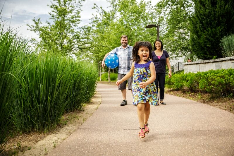 A family walking down a path with a little girl holding a balloon.