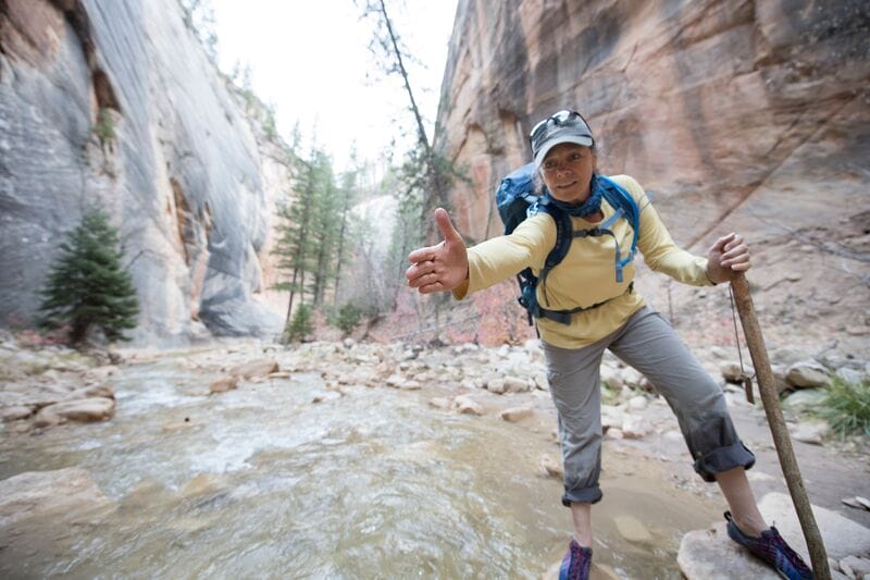 A woman hiking in a canyon with a backpack.