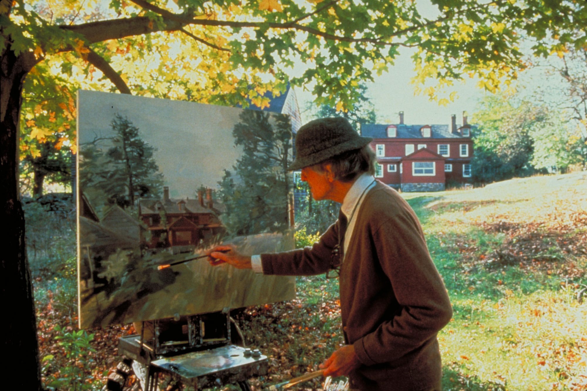 A man is painting in front of a house.