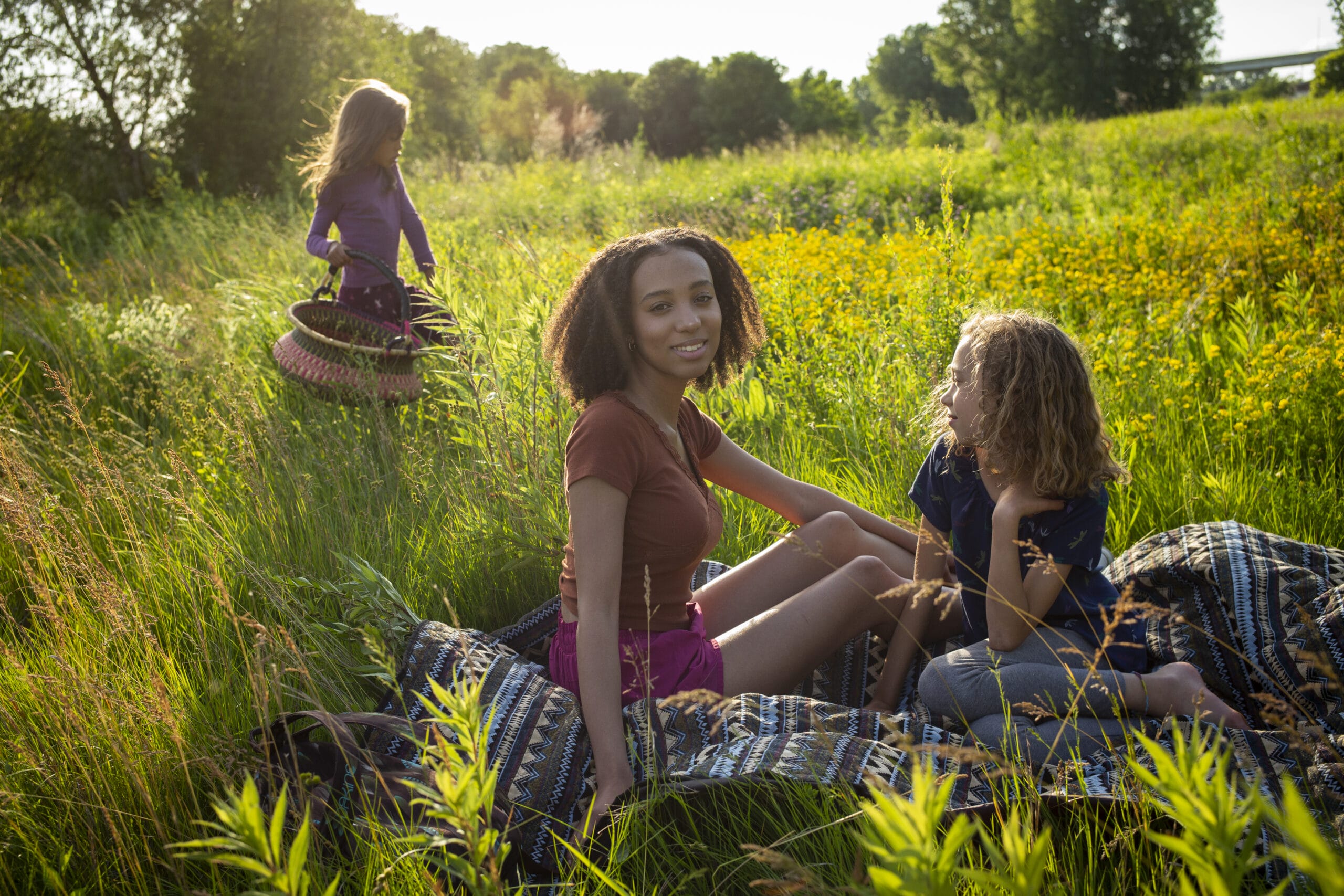 A family sits on a blanket in a field.