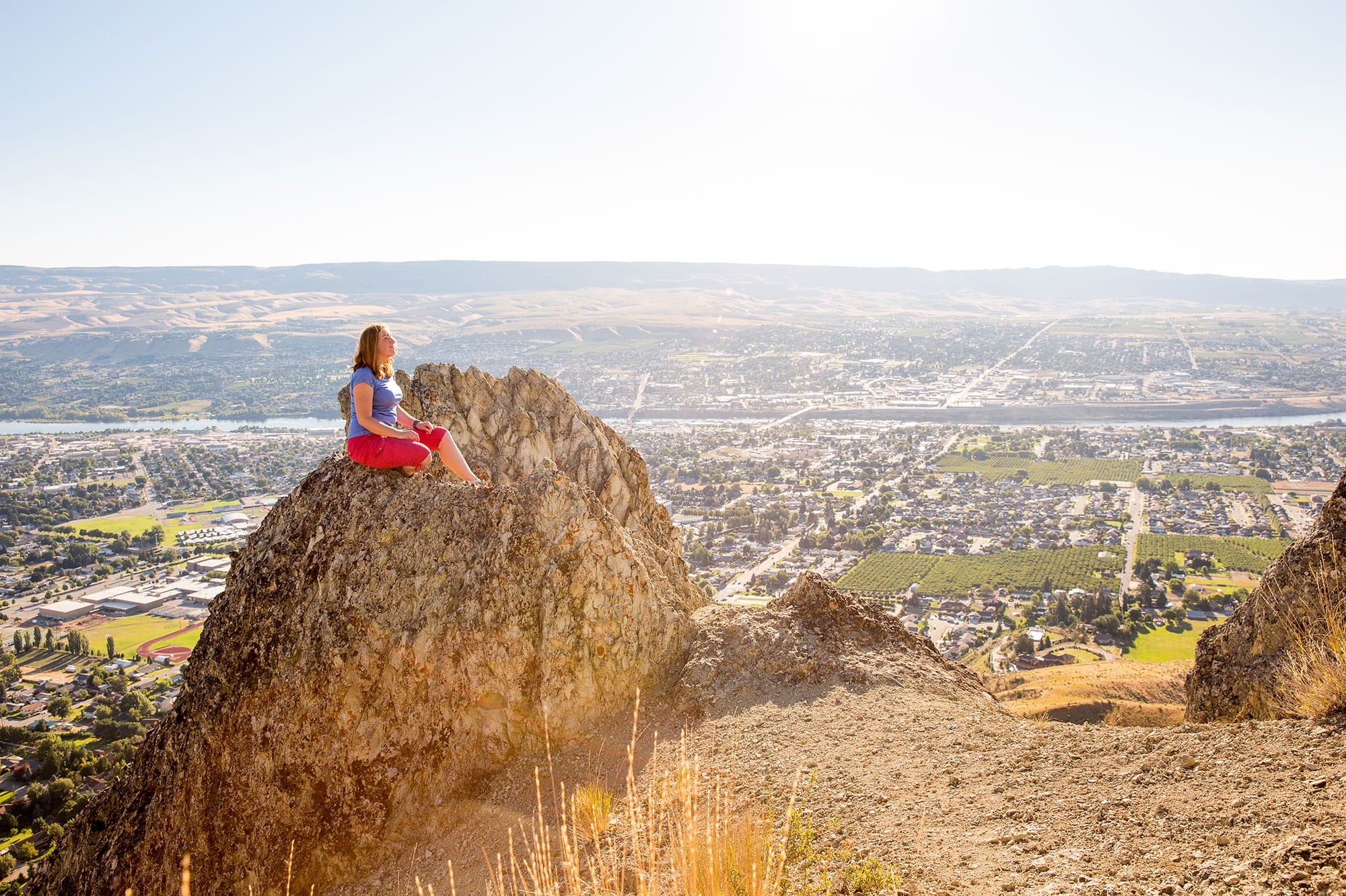 A woman sitting on top of a mountain.