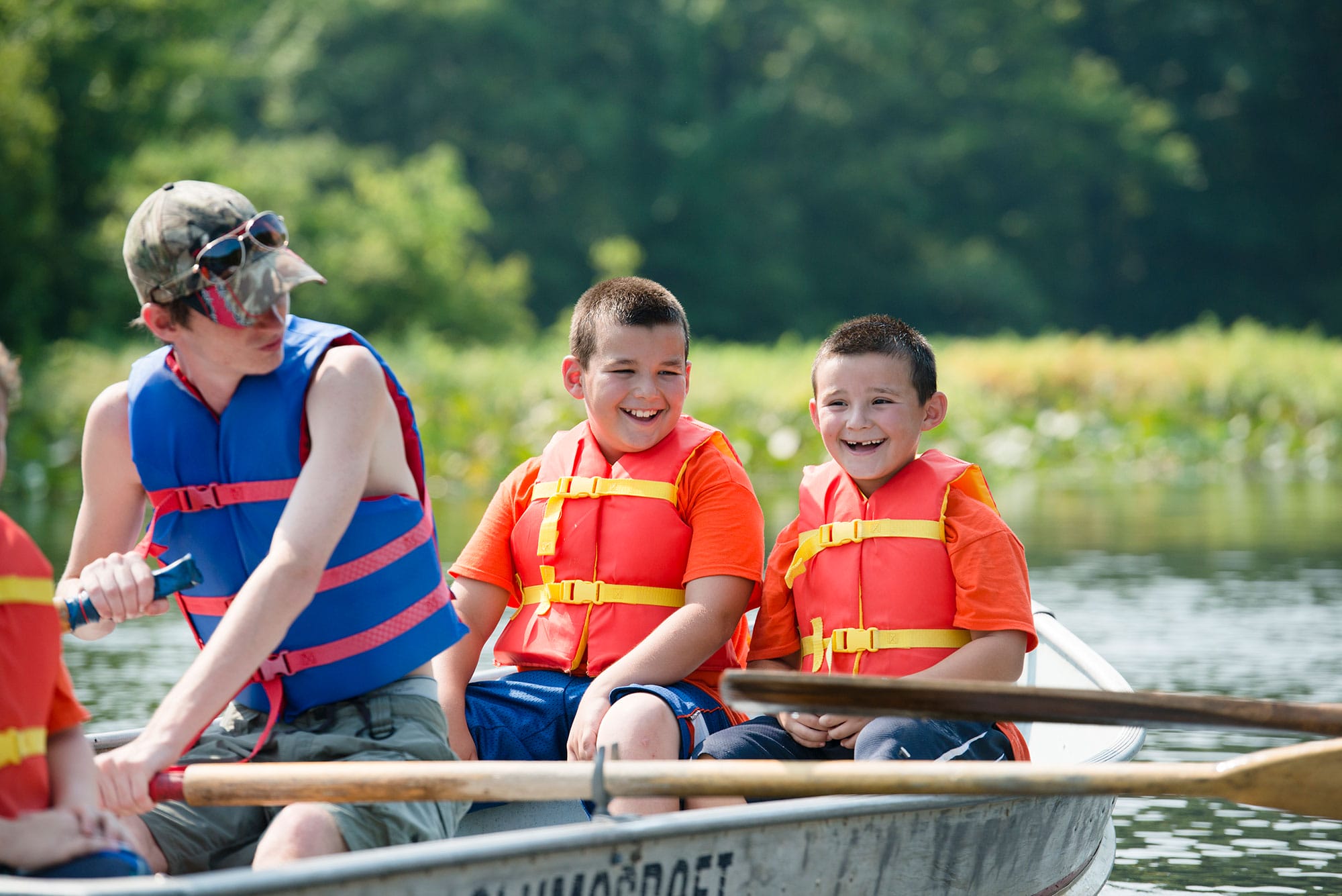 A group of boys in life jackets rowing a canoe.