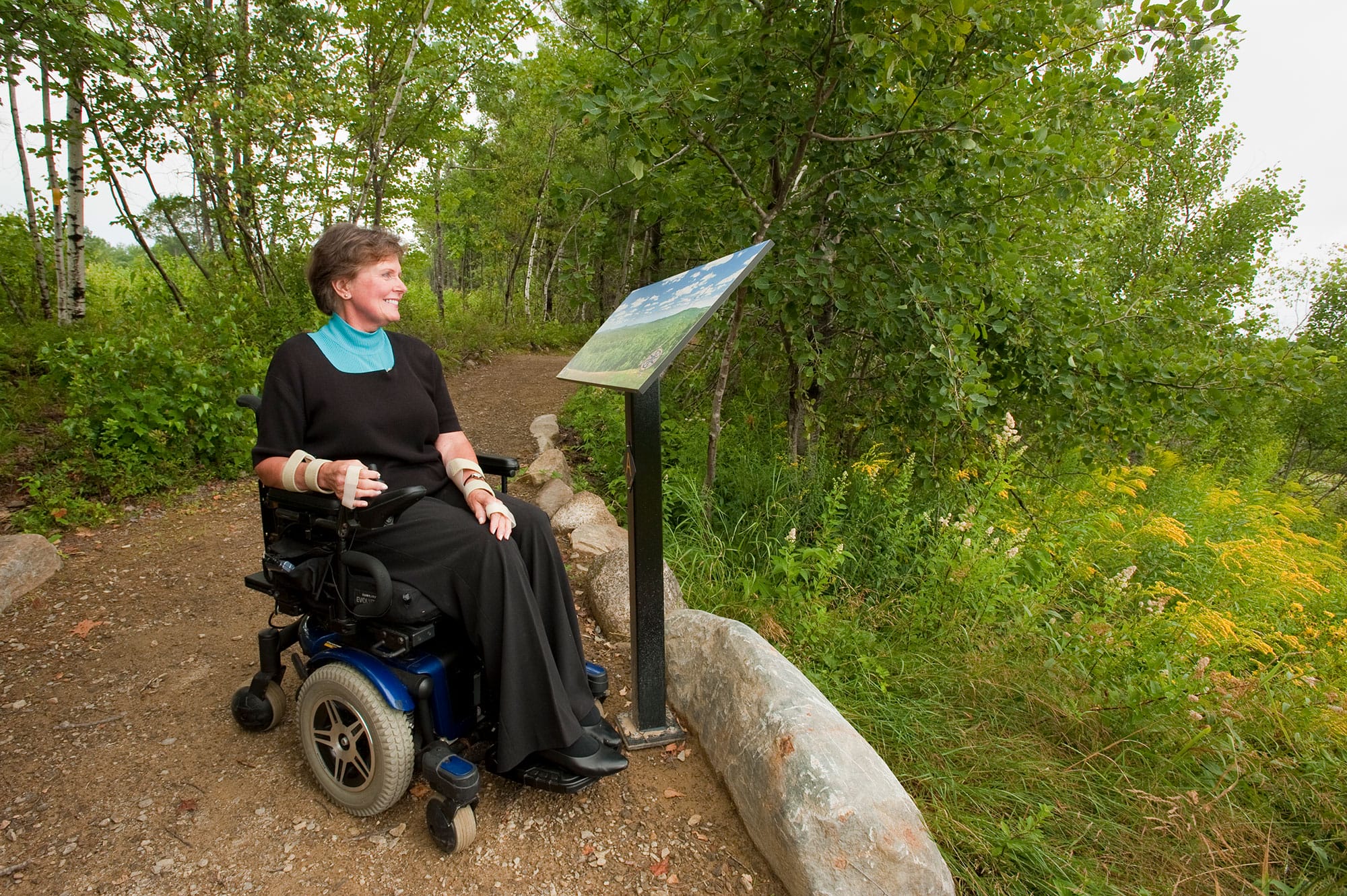 A woman in a wheel chair on a trail.