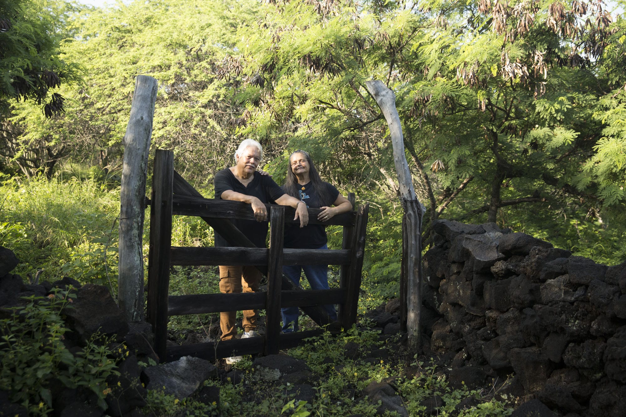 Two men standing in front of a wooden gate.