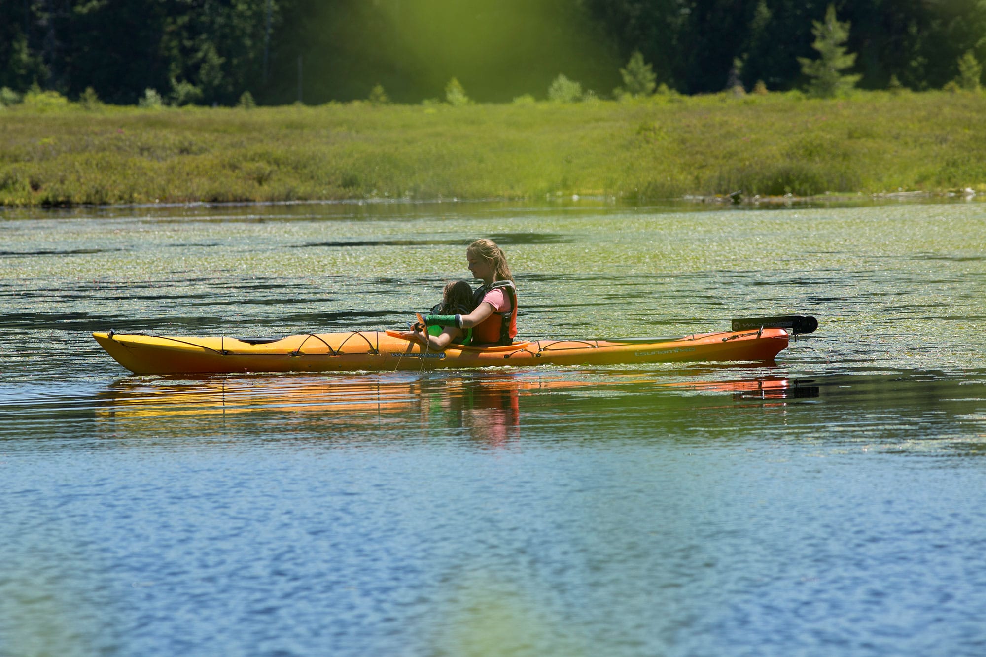 A woman is paddling a kayak in a body of water.