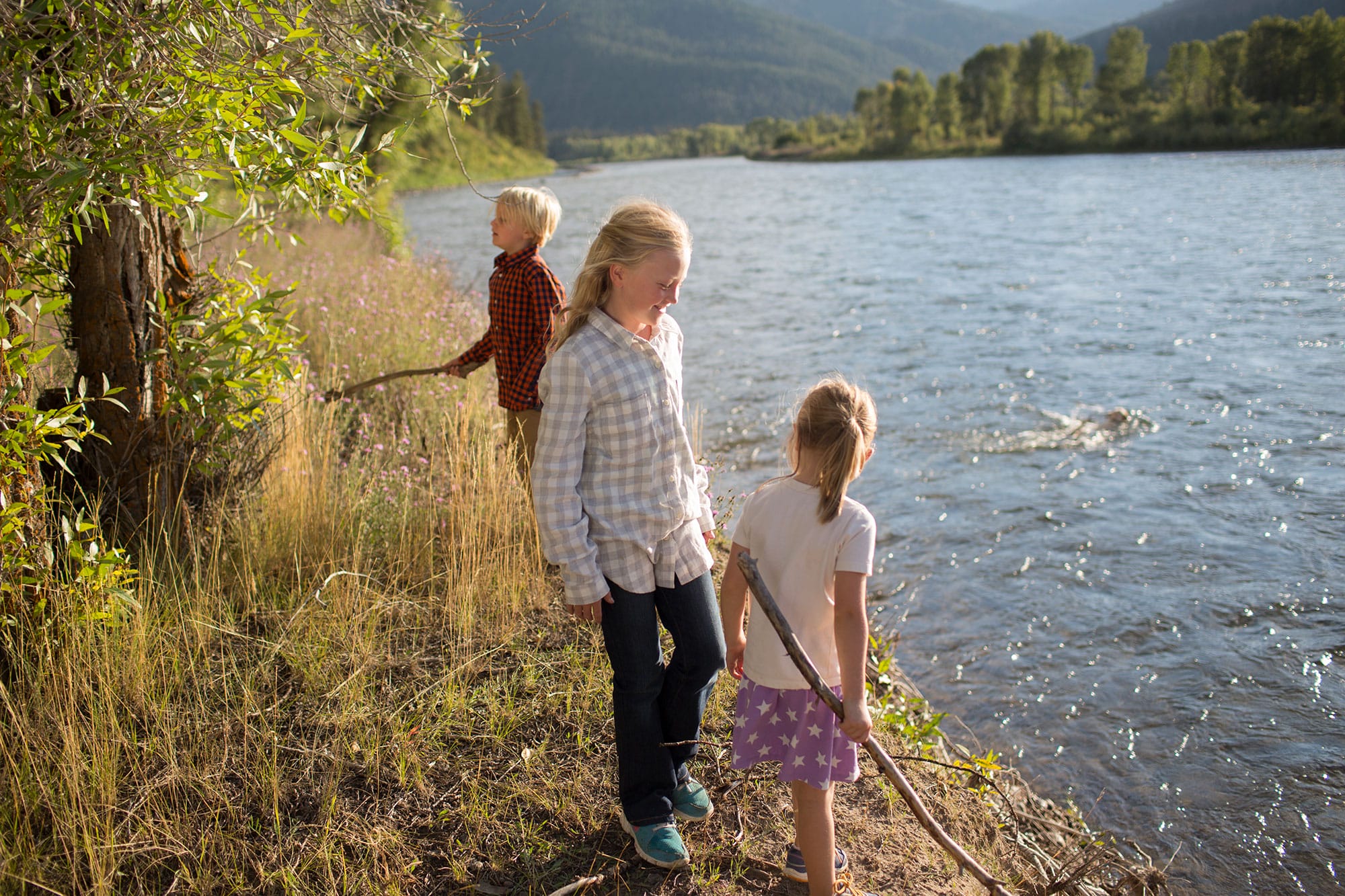 A group of children standing on the shore of a river.