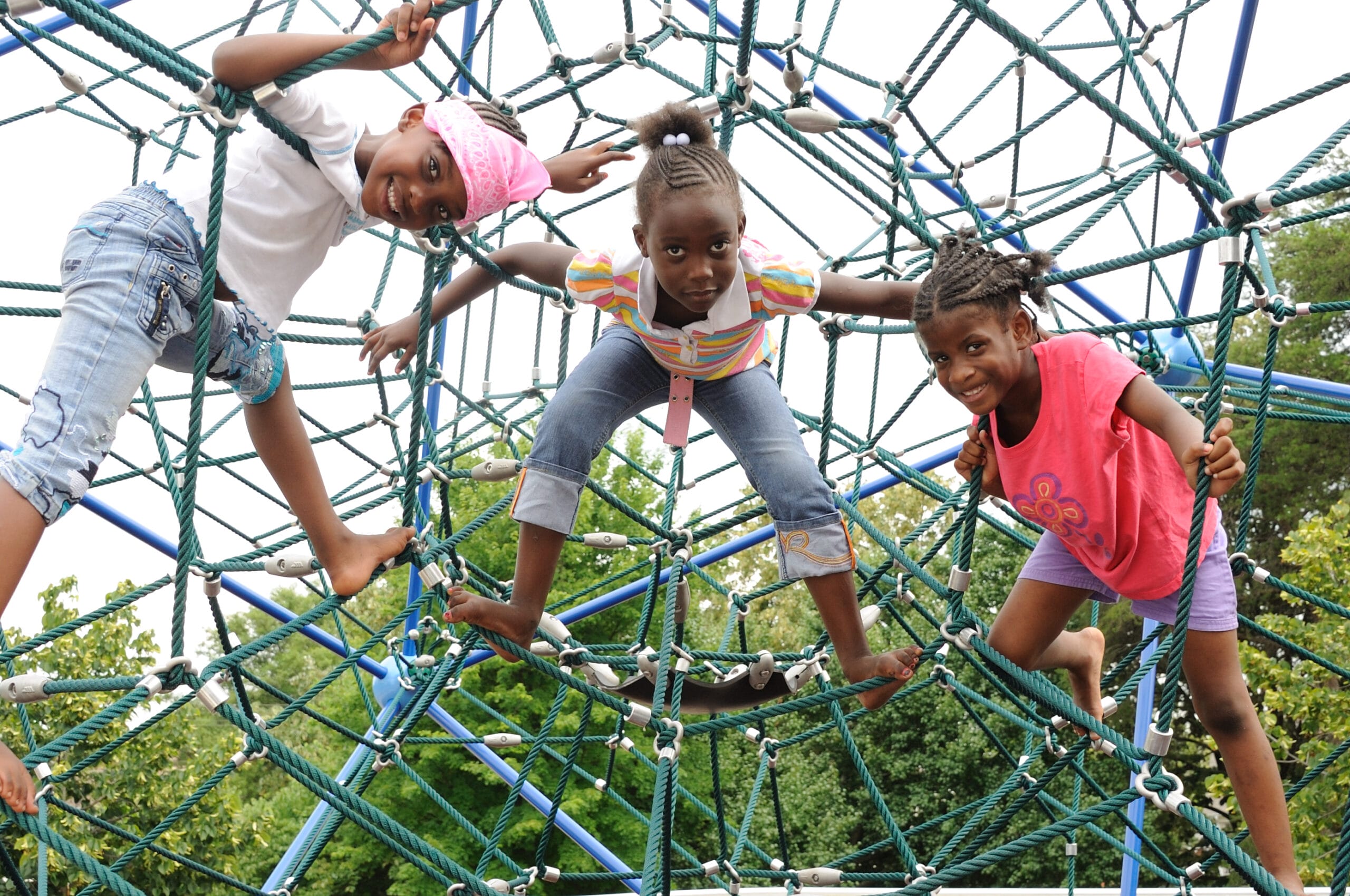 Three young girls playing on a playground structure.