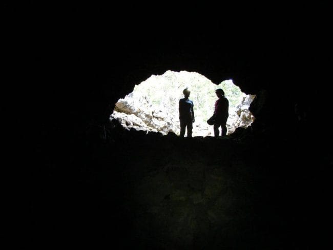 Two silhouetted figures in the mouth of a cave