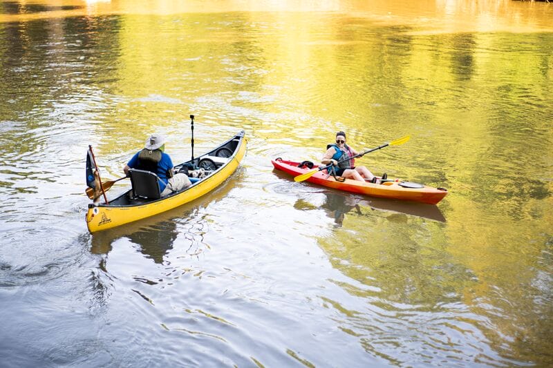 Two people kayaking down a river in a yellow canoe.