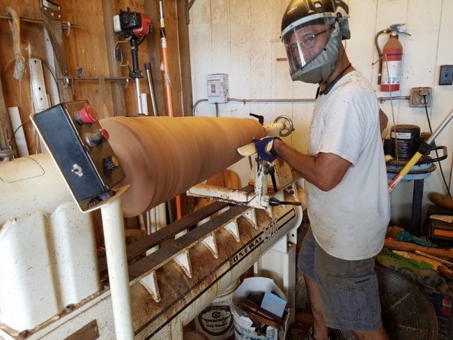 A man in a face mask at a lathe