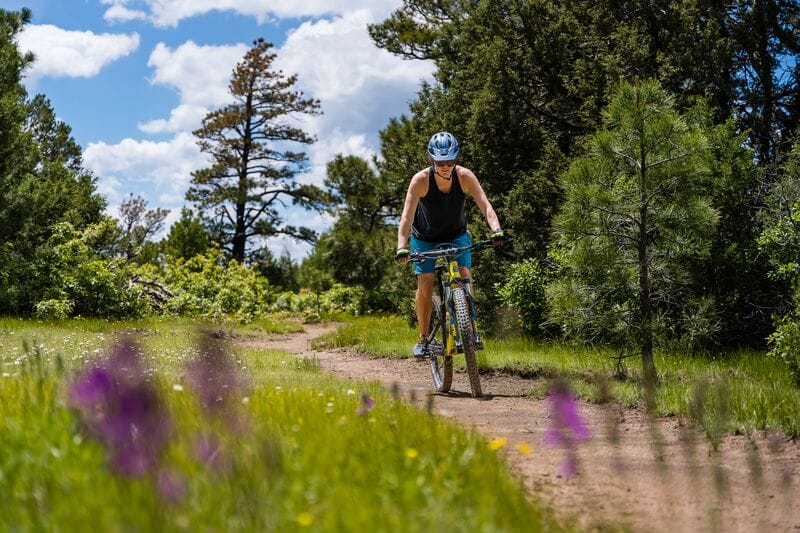 A woman riding a mountain bike on a dirt trail.