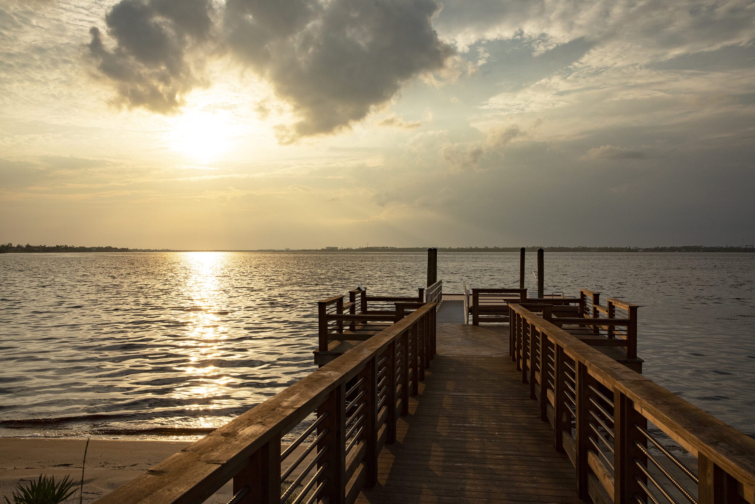 A dock leading to a body of water at sunset.