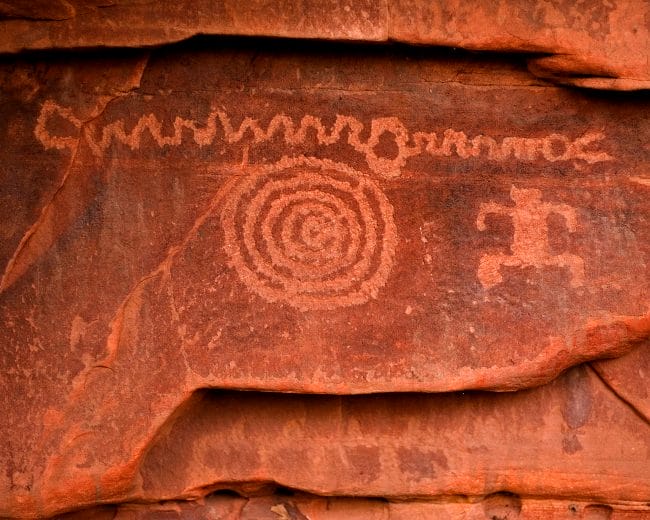 A rock art panel with a squiggly line, a human figure, and a spiral