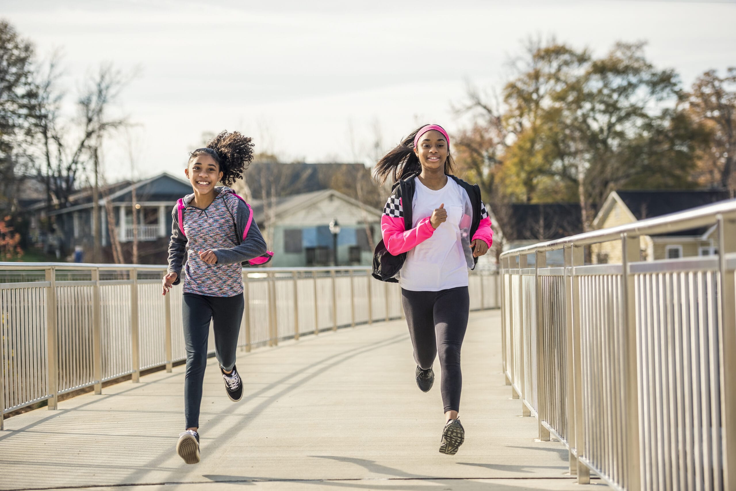 Two women jogging on a bridge.
