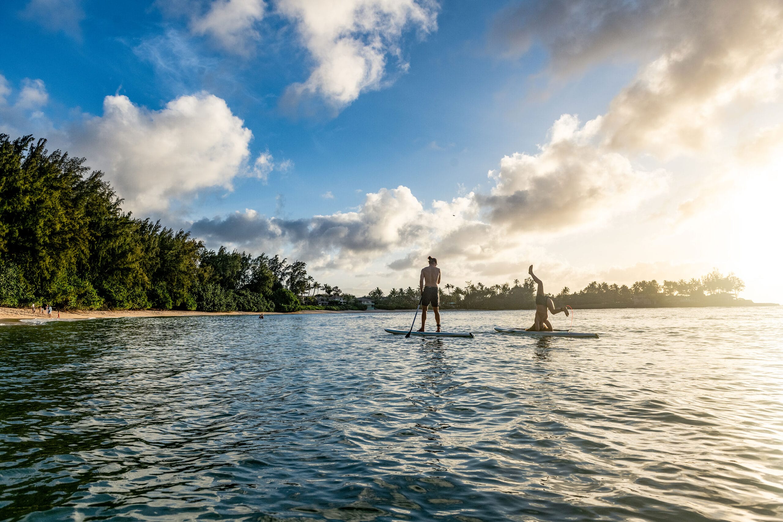 Two people stand up paddle boarding in the ocean.