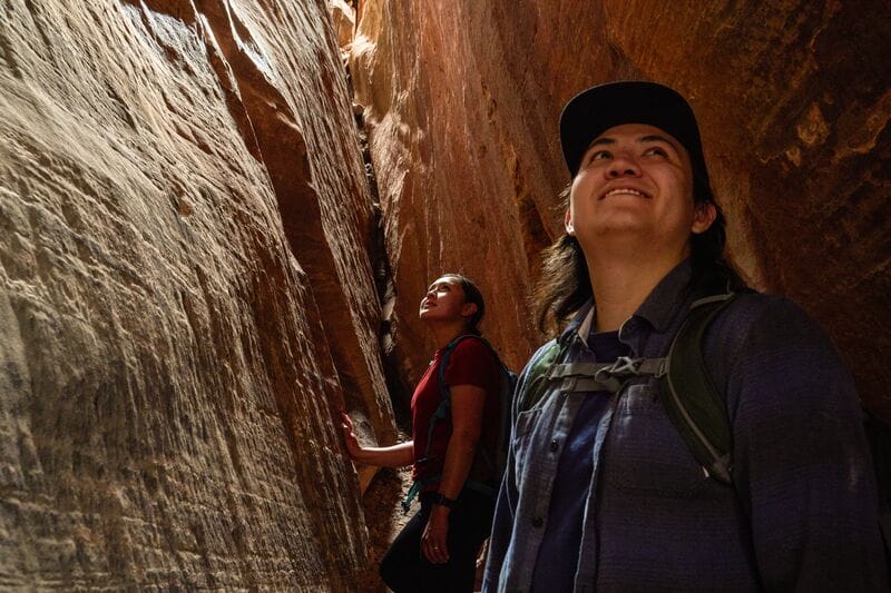 Two hikers standing in a narrow canyon.