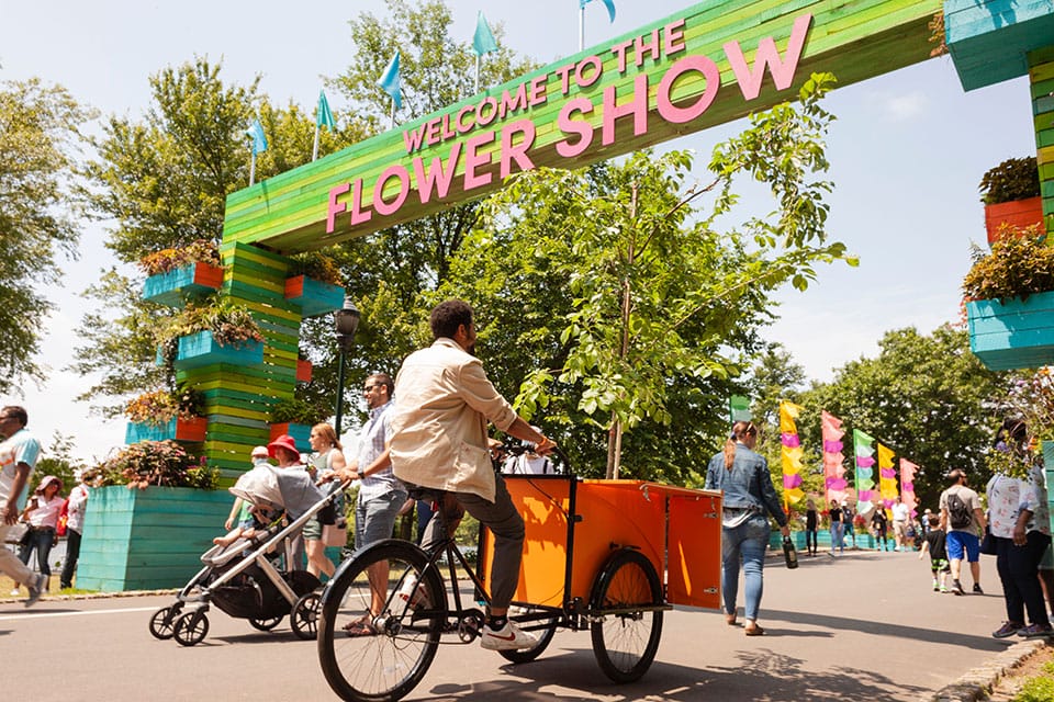 A man riding a bike through a flower show.