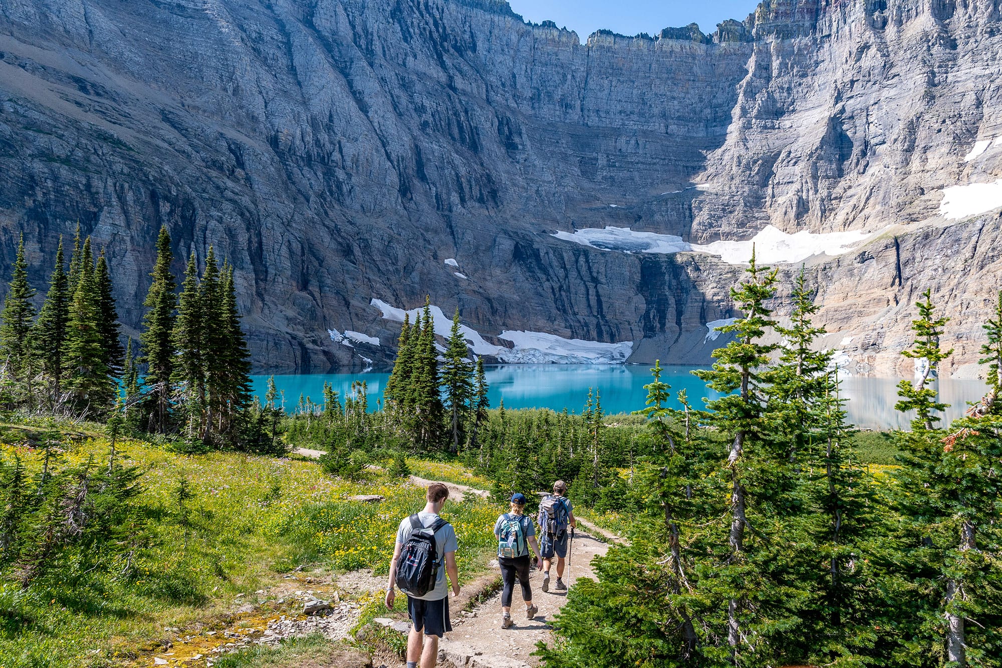 A group of visitors hike a trail in Glacier National Park.