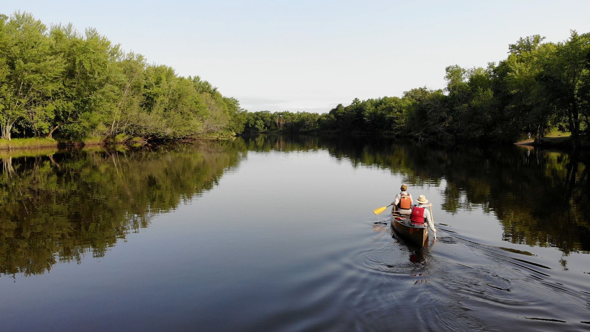 Two people are paddling a canoe down a river.