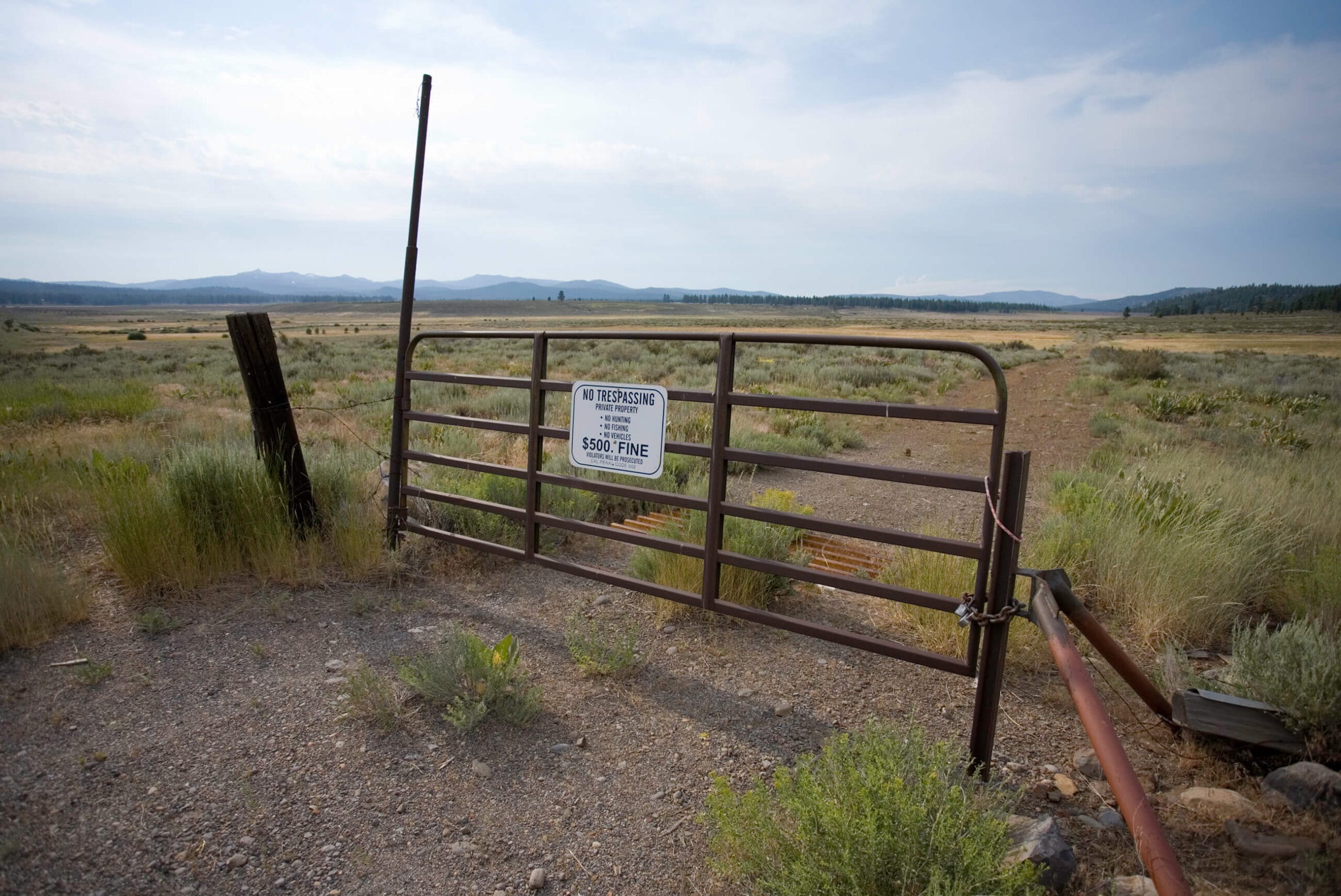 A gate with a sign in the middle of a field.