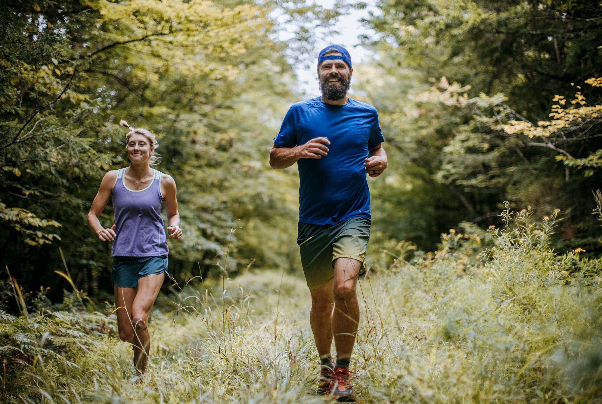 A man and woman jogging in the woods.