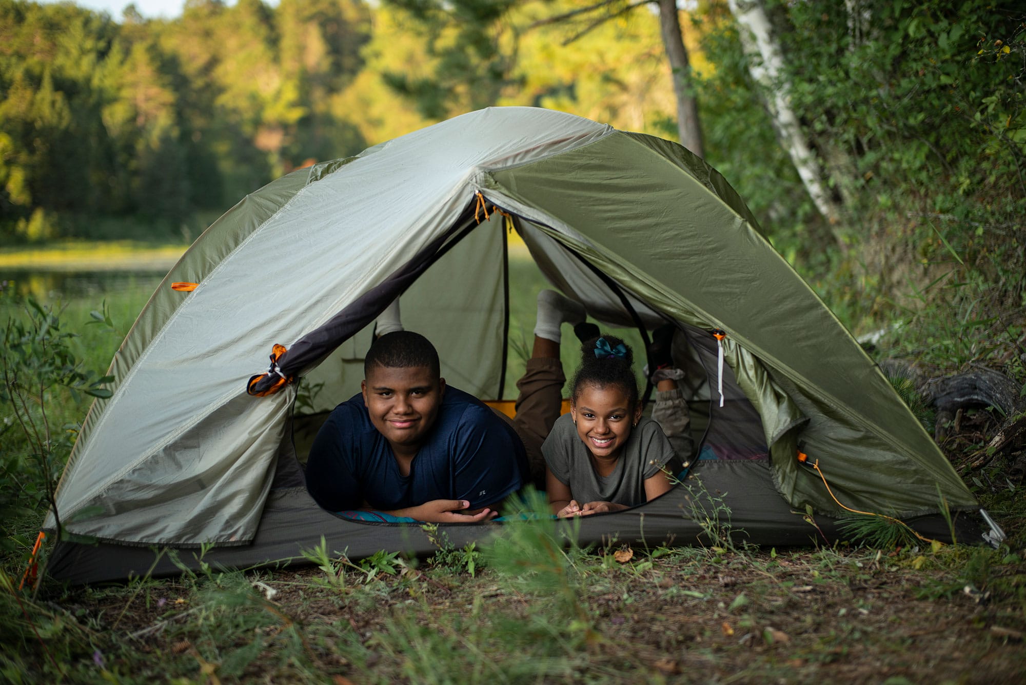 A boy and a girl sitting in a tent.