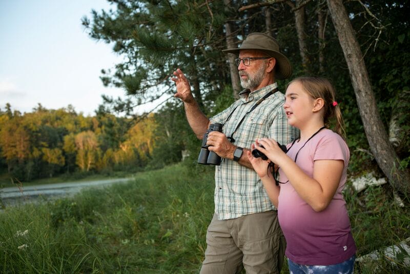 A man and a girl looking through binoculars.