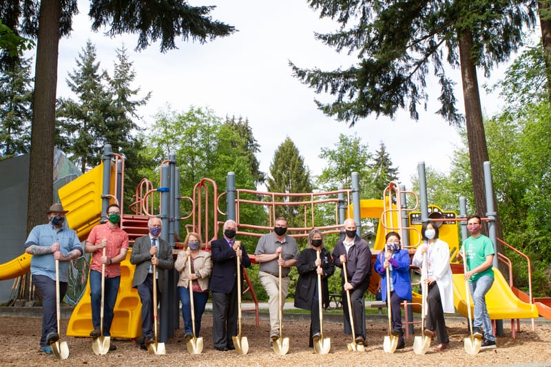 A group of people standing in front of a playground.