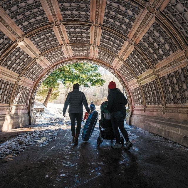 Two people walking through a tunnel in central park.