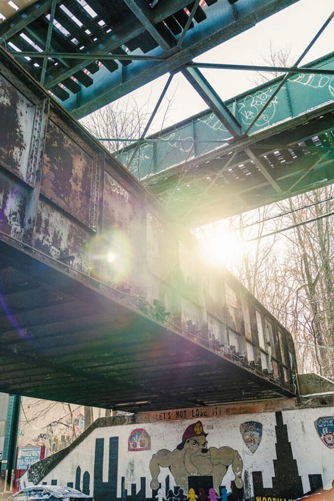 A man is riding a skateboard under a bridge.
