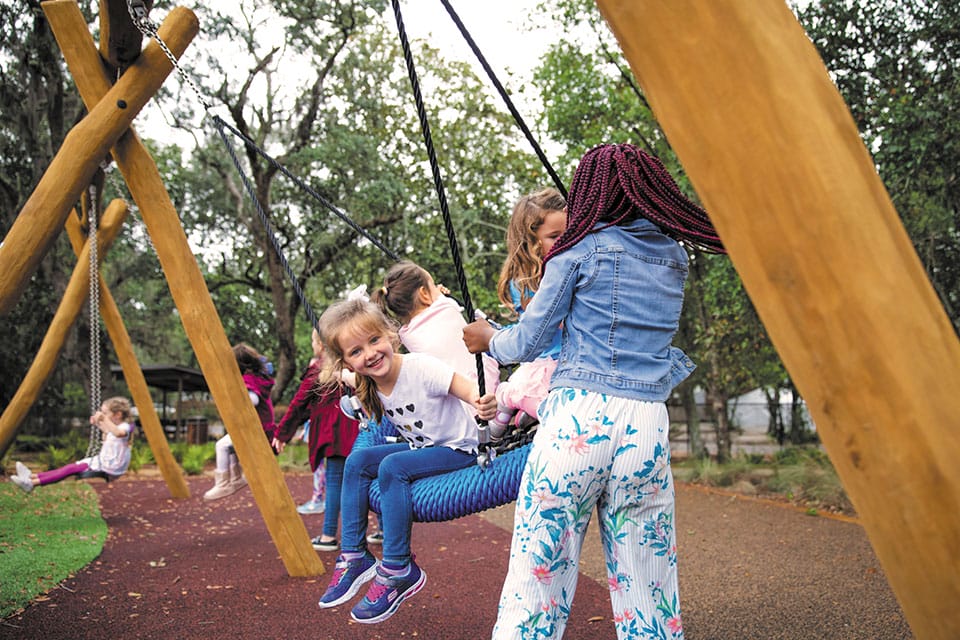 A group of children playing on swings in a park.