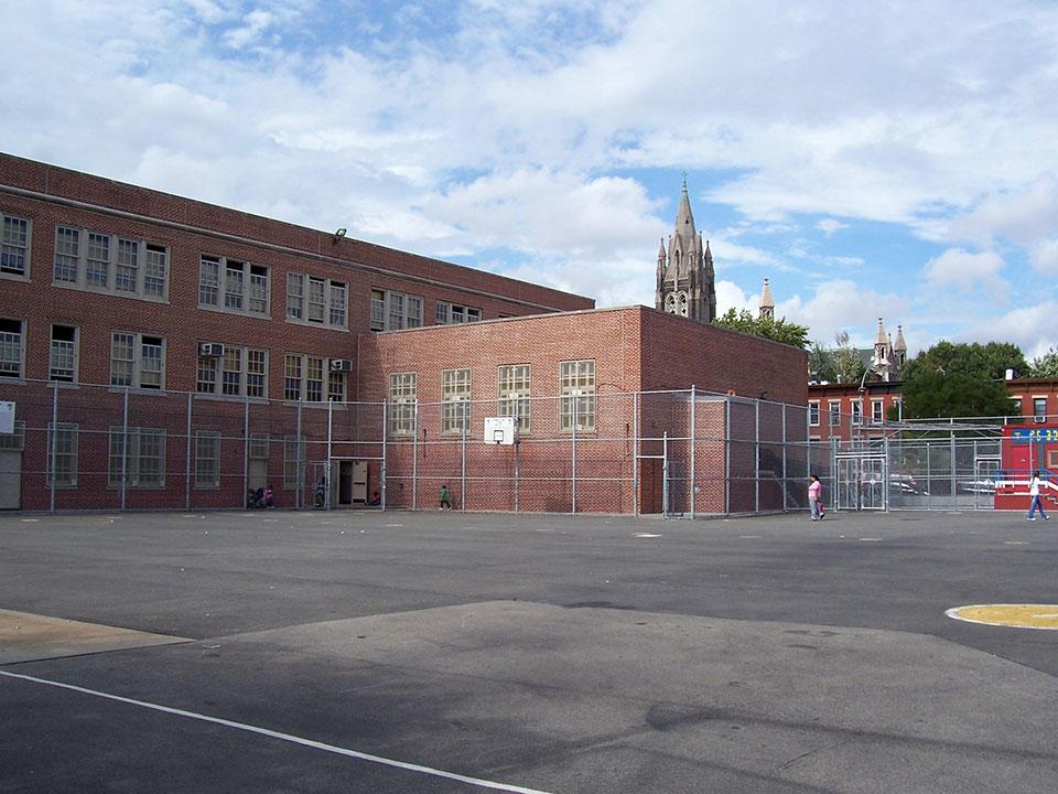 A basketball court in front of a brick building.