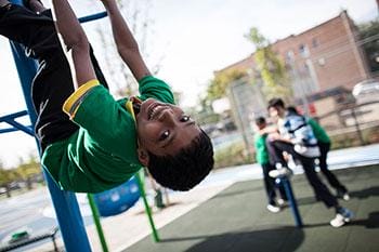 A boy is hanging from a rope in a playground.