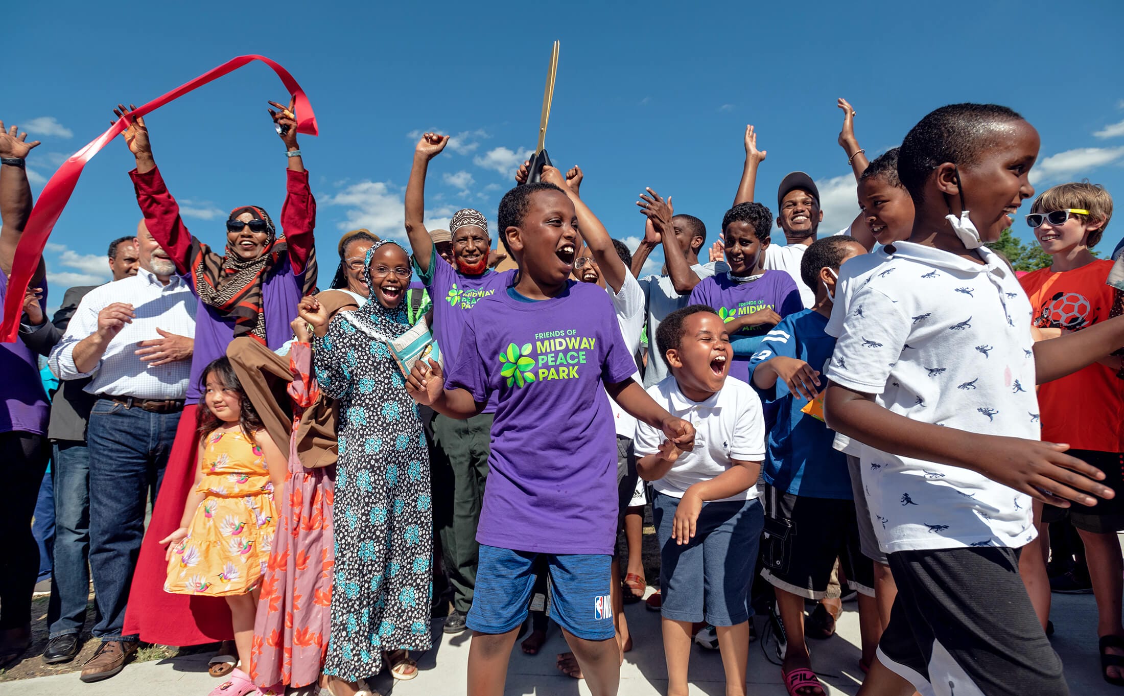 A group of children are celebrating a ribbon cutting ceremony.