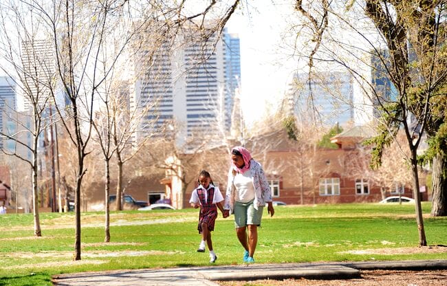 A woman walks in a park with her granddaughter