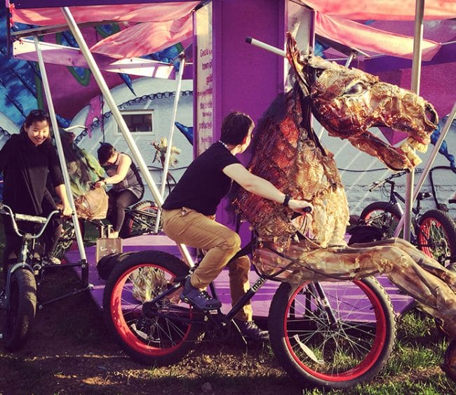 People ride a pedal-powered carousel