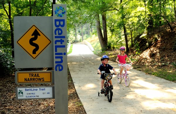 Two children riding bikes on a trail in the woods.
