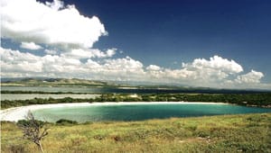 A blue lake in the middle of a grassy hill.