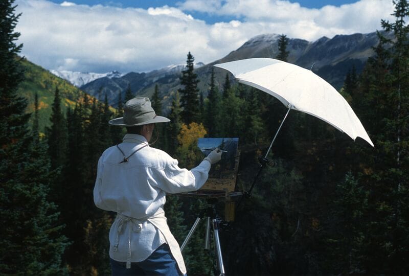 A man holding an umbrella in front of a mountain.