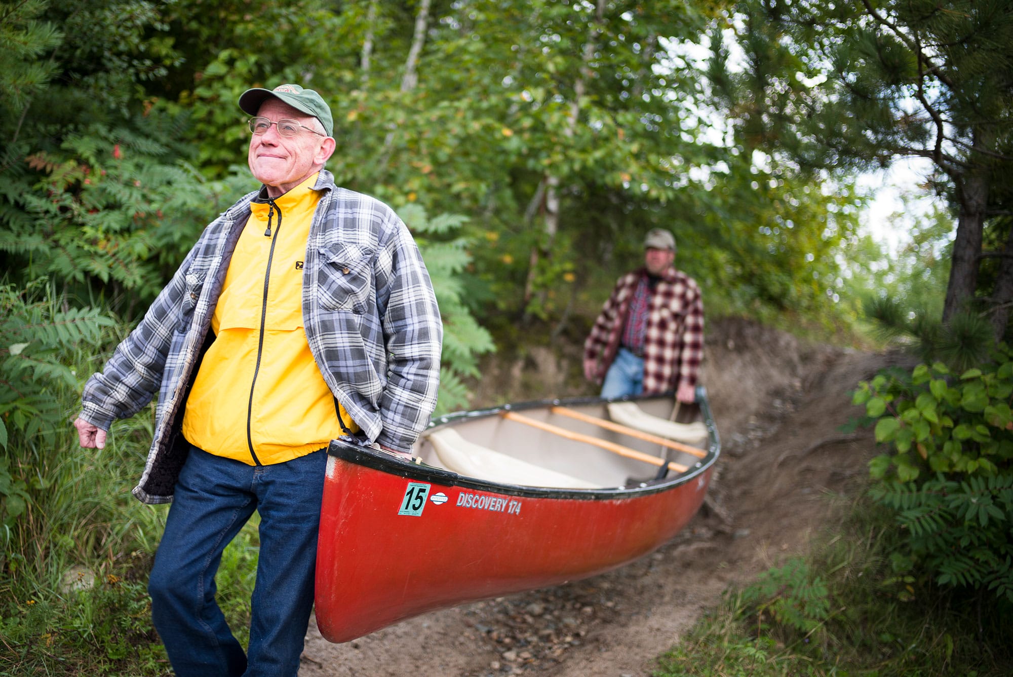 A man carrying a canoe down a trail.