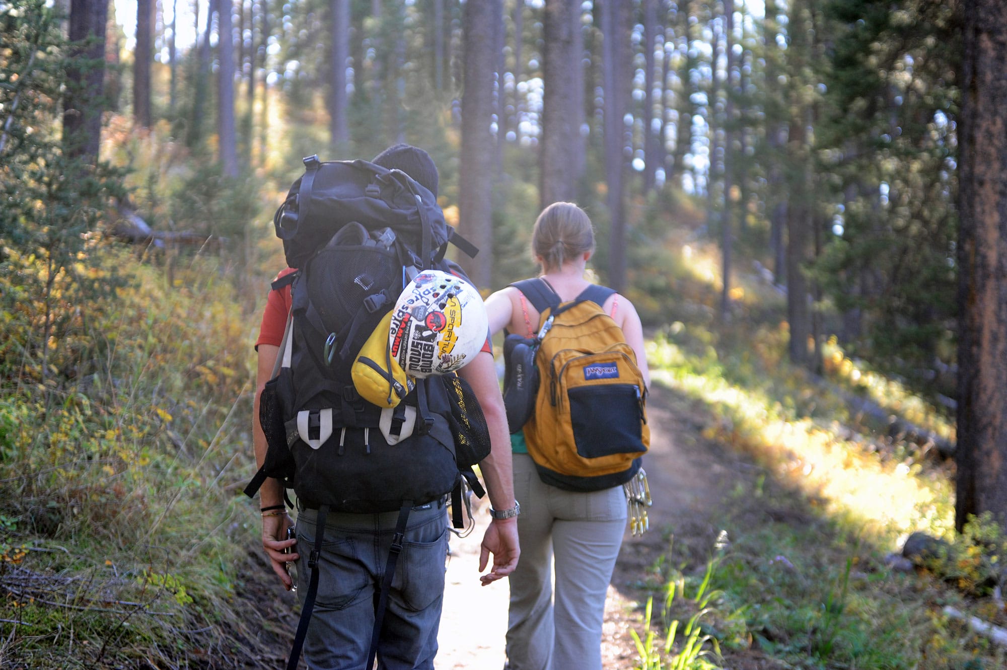 Two people walking down a trail with backpacks.