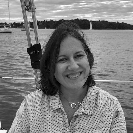 Black and white photo of a woman smiling on a sailboat.