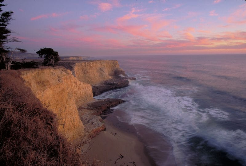 A cliff overlooking the ocean at sunset.