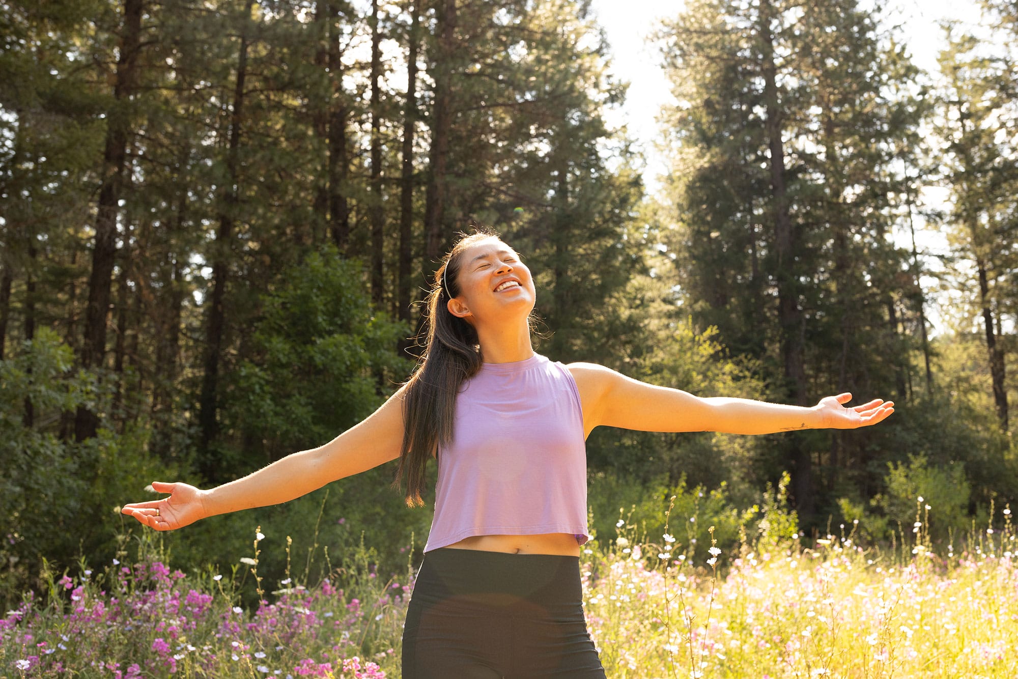 A woman standing in a field with her arms outstretched.