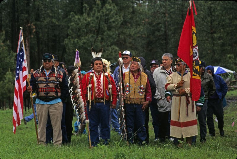 A group of native americans standing in a field with flags.
