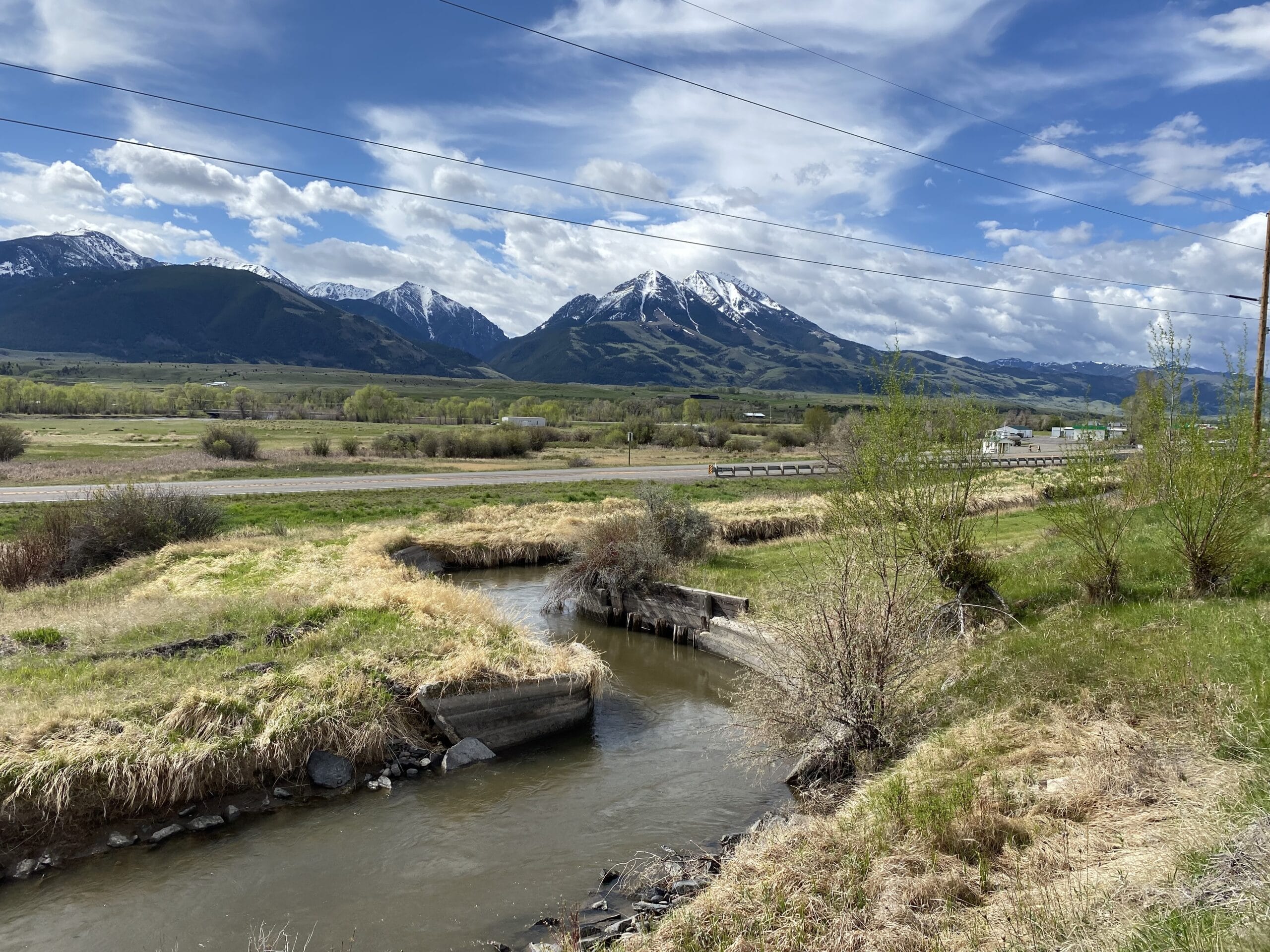 A stream in the middle of a field with mountains in the background.