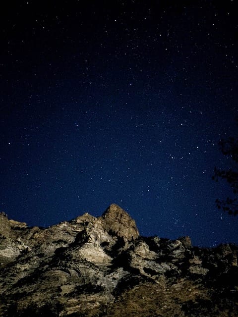 A night sky with stars above a mountain range.